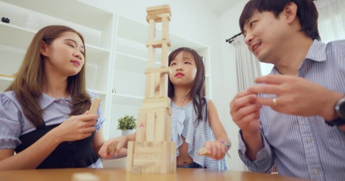 Focused grandparents and their granddaughter are deeply engaged in playing a thrilling block-stacking board game together.
