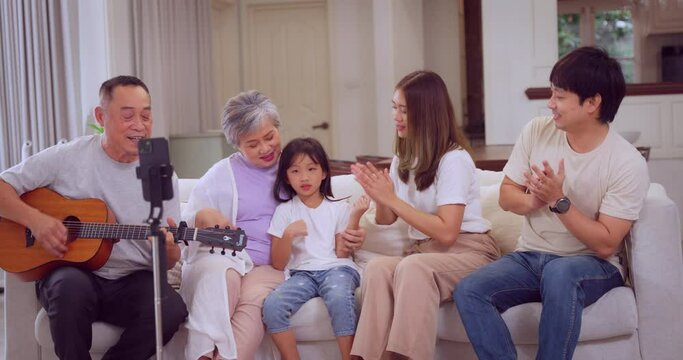 Multi-generational family happily engaging in music, with a man playing guitar surrounded by relatives.