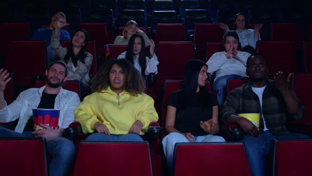 The audience in the cinema is judging, something has gone wrong and the audience in the cinema is annoyed, slow motion of the audience in the cinema is upset. The premiere was a failure.