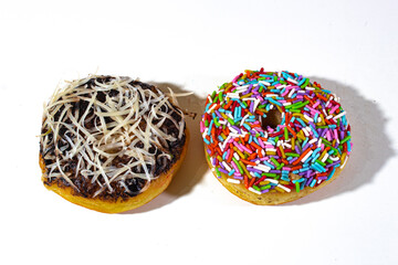 two donuts with chocolate peanut topping and colorful sprinkles, on a plain white backgorund - Powered by Adobe