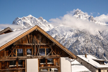 Alpine mountain panorama in winter.  Traditional Engadine farmhouse in front of the Swiss Alpine...