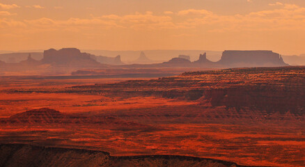 Spectacular afternoon view of the distant buttes and mesas of Monument Valley just beyond the Goosenecks of the San Juan river from Muley Point viewpoint, Utah, Southwest USA. - obrazy, fototapety, plakaty