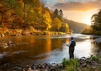 autumn river at sunset and a fisherman