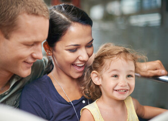 Amusement park, smile and happiness for family in ride, mother and father together with cute toddler. Holiday, woman and man with girl in roller coaster for fun, laughter and joy with child in USA