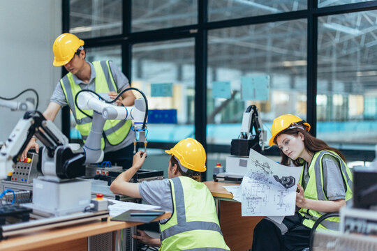 Trainees programing robotic arm in practical lesson at robotics academy, focusing on hands-on skills