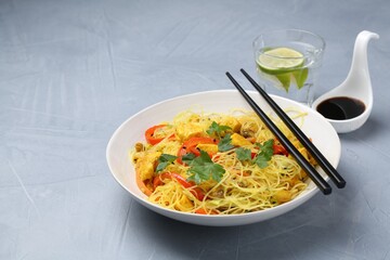 Stir-fry. Delicious cooked noodles with chicken and vegetables in bowl served on gray textured table, space for text
