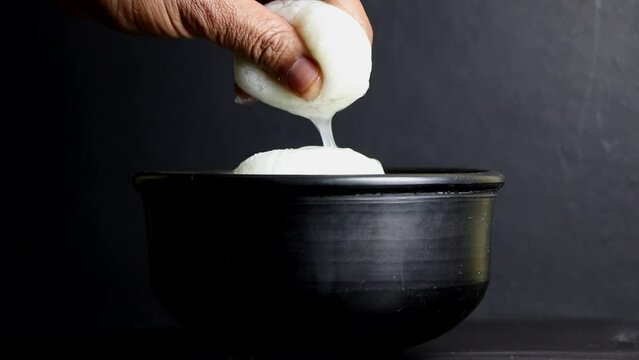 squeezing a spongy Rasgulla one of the popular Indian sweet.