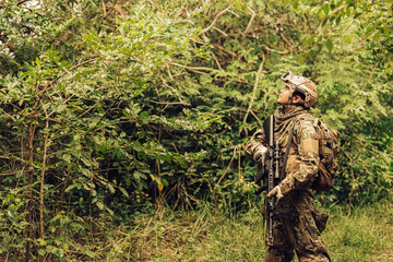 Soldiers from the Royal Thai Army reconnoitre enemies in a jungle battlefield, carrying M16 rifles. Ready to shoot enemies wearing camouflage uniforms, military helmets, and vision goggles.