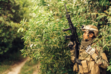 SEAL leader holds M16 gun Wait for reinforcements to help, tactically hide in the bushes, listen for enemy footsteps and engage in dangerous battlefields of US Army military battles.