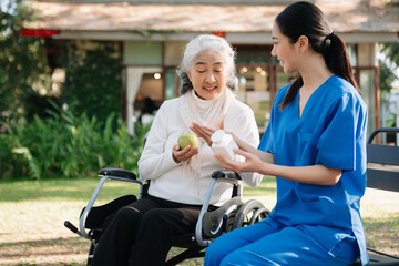 Fototapeta na wymiar Elderly asian senior woman on wheelchair with Asian careful caregiver. Nursing home hospital