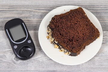 Glucometer for measuring sugar level and sweet chocolate cake. Nutrition during diabetes