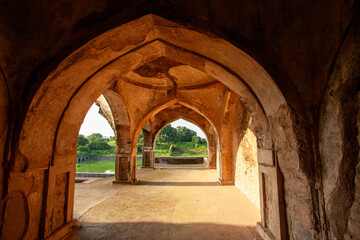 The arched doorway of a building with a view of the sunset, Mandu, India.