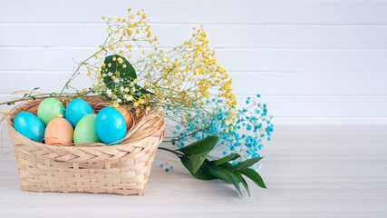 Banner. Easter eggs, feathers in a nest on a white wooden background. The minimal concept. Card with a copy of the place for the text.