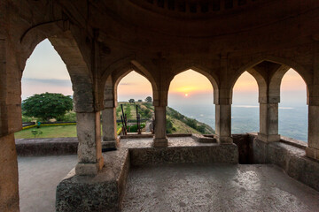 The arched doorway of a building with a view of the sunset, Mandu, India.