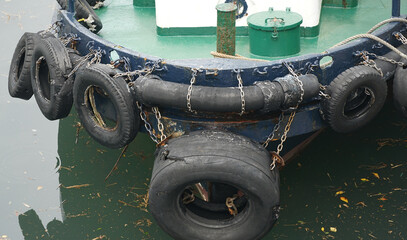 The bow of a tireed tugboat docked in the harbor