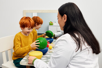 Male child with ASD working with sensory therapist using hedgehog half balls. Sensory integration therapy in pediatric rehabilitation