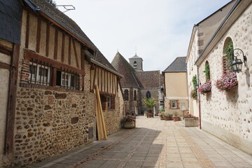 old street in the village by the half timbered buildings  and church in france 