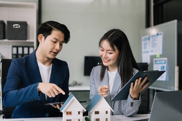 Real estate broker agent presenting and consult to customer to decision making sign insurance form agreement, home model, concerning mortgage loan offer in office.