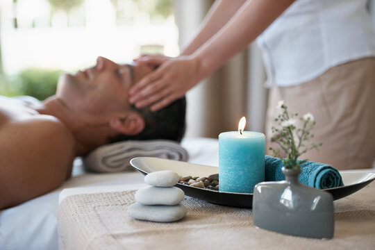 Luxury, facial massage and man relax in spa with aromatherapy candle for holistic treatment. Hotel, peace and health for male person, wellness and rest in resort for holiday for skincare in break