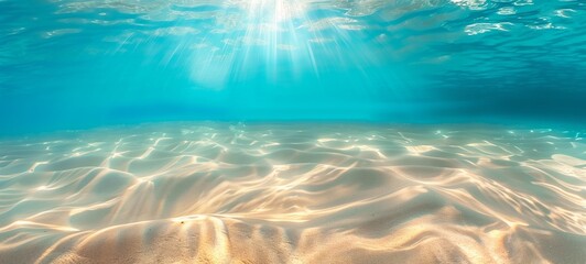 Fototapeta na wymiar Underwater view of sun rays filtering through the blue ocean, illuminating the sandy seabed with a clear gradient from light to dark. Concept of marine environment