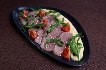 Duck breast with arugula, cherry tomatoes, and sesame seeds on a creamy sauce