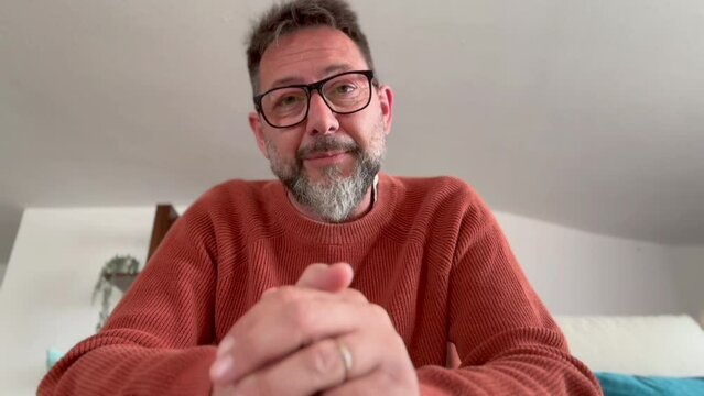 Mature older man virtual psychologist teacher consulting patient teaching student looking talking to camera make conference call recording video training sit on sofa at home office, webcam view