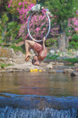 Beautiful Asian girl performing show aerial hoop or aerial ring in various positions and spinning stunts on the blue sky.
