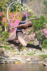 Beautiful Asian girl performing show aerial hoop or aerial ring in various positions and spinning stunts on the blue sky.