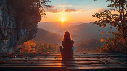 Nature background a woman sitting on wooden porch extending into a high mountain cliff with beautiful warm orange light of sun.