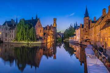 Evening atmosphere in the old town of Bruges. Canal of the Rosary Quay in the Hanseatic city. Reflection on the water surface of the historic buildings with tower belfry - obrazy, fototapety, plakaty