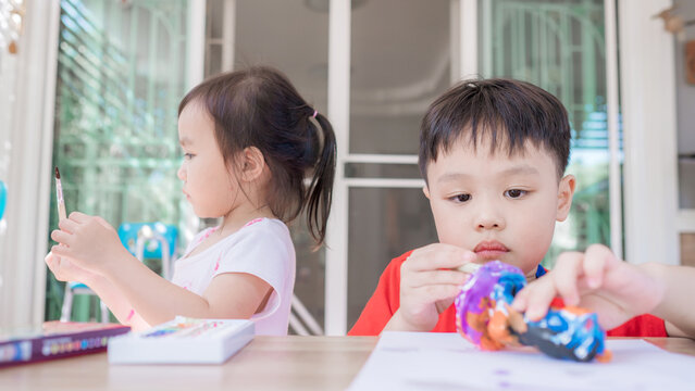 Cute little boy and girl painting color on DIY plaster painting toy at home. Soft focus. Copy space.