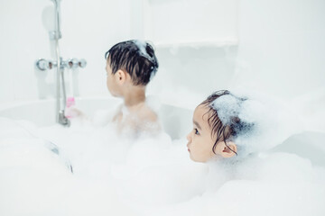 Cute little boy and girl taking bath playing with foam and soap bubbles. Hygiene for infant and baby. Soft focus. Copy space.	