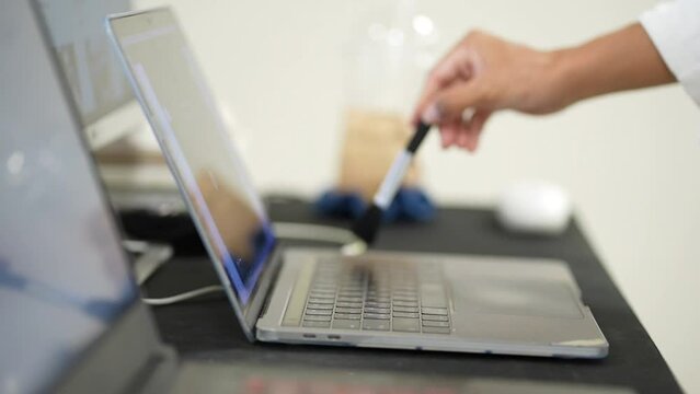 Cleaning the laptop. A female hand cleans the laptob.Technology, health and closeup of female person wipe computer with Soft brush in workplace.