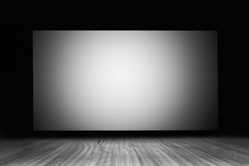 an empty white screen on a wooden stage in a movie theater black white photography