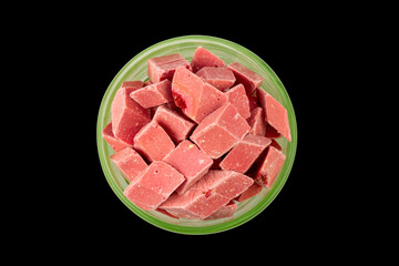 pink pieces of Uzbek dairy strawberry halva in a green bowl isolated on a black background top view
