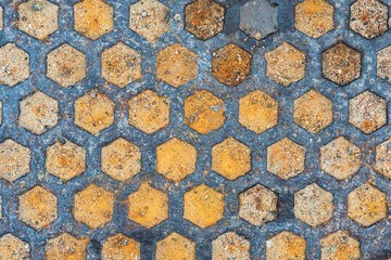 Close-up of a fragment of a cast iron sewer cover. Dark metal honeycomb design. The depressions are filled with sand mixture. Background. Form.