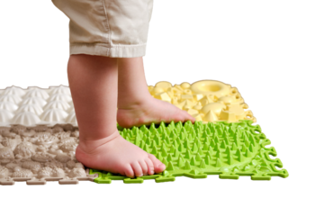 Baby toddler foots close-up on a medical orthopedic mat, isolated on white background. Child legs with flat feet on a medical rug, isolated on white background. Kid aged one year four months