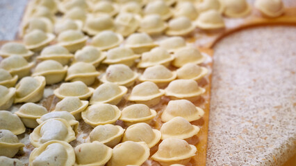 Homemade dumplings close-up. handmade dumplings on a wooden board, selective focus, tinted image, traditional Russian dish,