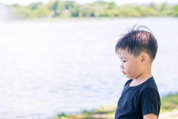 Cute asian child lying at park. Sad lonely boy. Nature background. Copy space.