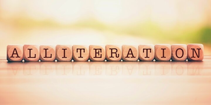 alliteration word made with building blocks. Wooden Blocks with the text: alliteration. The text is written in black letters.