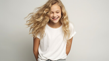 Fototapeta premium Smiling teenage girl in a white T-shirt on a white background mockup. Childhood lifestyle concept. Mockup&nbsp;copy&nbsp;space. Scandinavian girl model