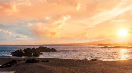 beautiful coast beach with sea gulf water during sunset or sunrise with golden sand, nice black rocks and stones, colorful vawes and clouds in thr sky