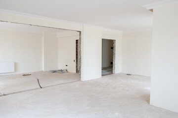 Apartment under construction with white painted walls and raw concrete floors