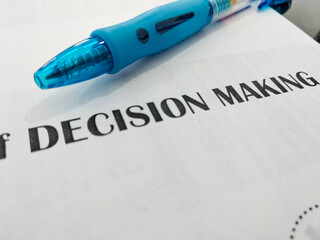 Obraz premium Close-up shot of a pen on white paper with the words DECISION MAKING. concept for business, project, and management