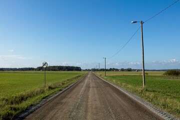 Rural gravel road between agricultural fields in summer, Ruotsinkylä, Ruotsinpyhtää, Finland.