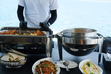 Outdoor Dining Service on a Luxury Yacht. A service attendant on a yacht arranges a meal with an...
