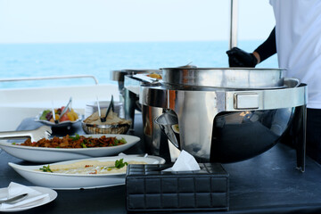 Luxury Yacht Catering with Ocean Backdrop. Elegant catering setup on a yacht's deck, with a...
