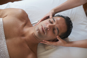 Hands, head massage and top view of man at salon for skincare, peace and calm at luxury resort at...