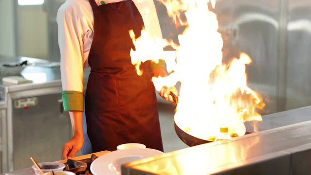 Thai Asian man professional chef cooking meal with fire at kitchen restaurant. culinary classroom. cooking school. cooking lessons in a cooking school.