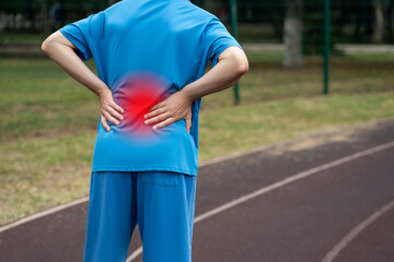 Back pain, kidney inflammation, man suffering from backache on a sports ground after workout